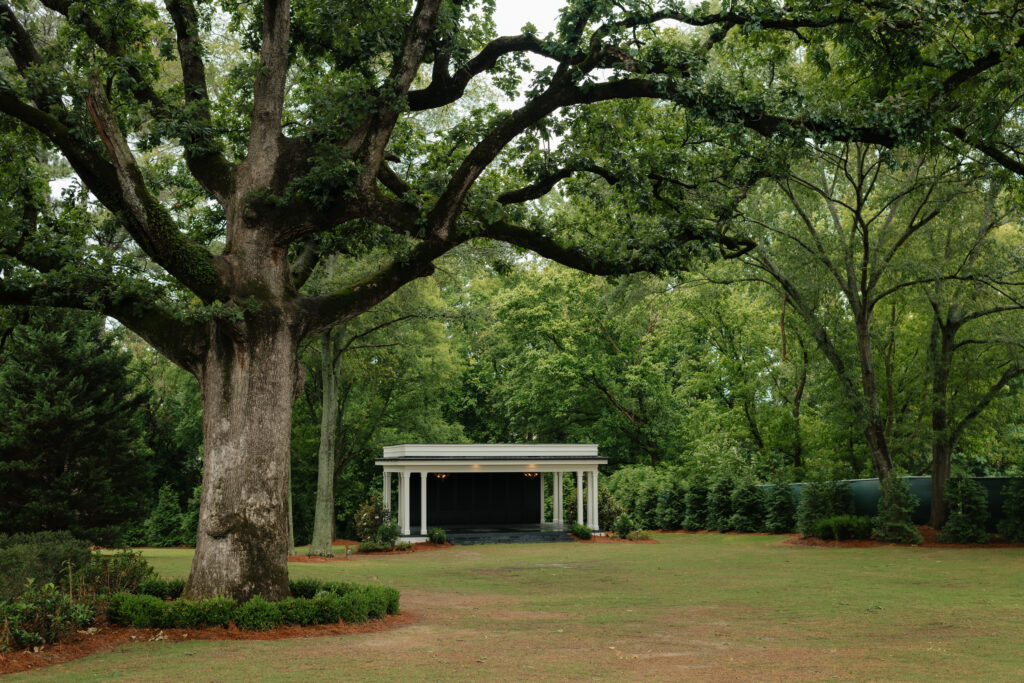 the backyard of the lumpkin house wedding venue in albertville, alabama, featuring their lawn, live oak, and ceremony space with white pergola