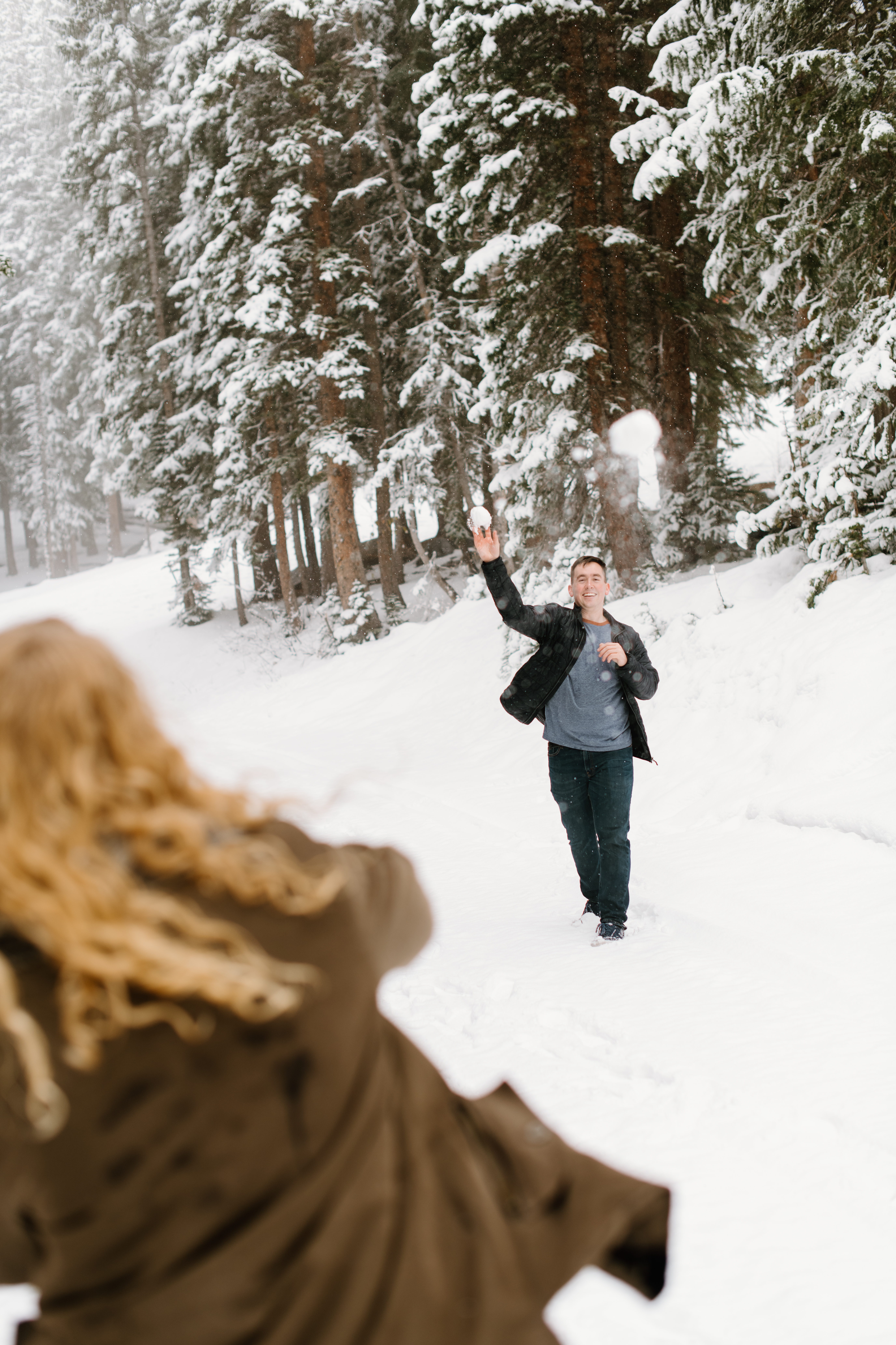 a couple throws snowballs at each other during their engagement photos with mt rainier engagement photographer sarah mismash
