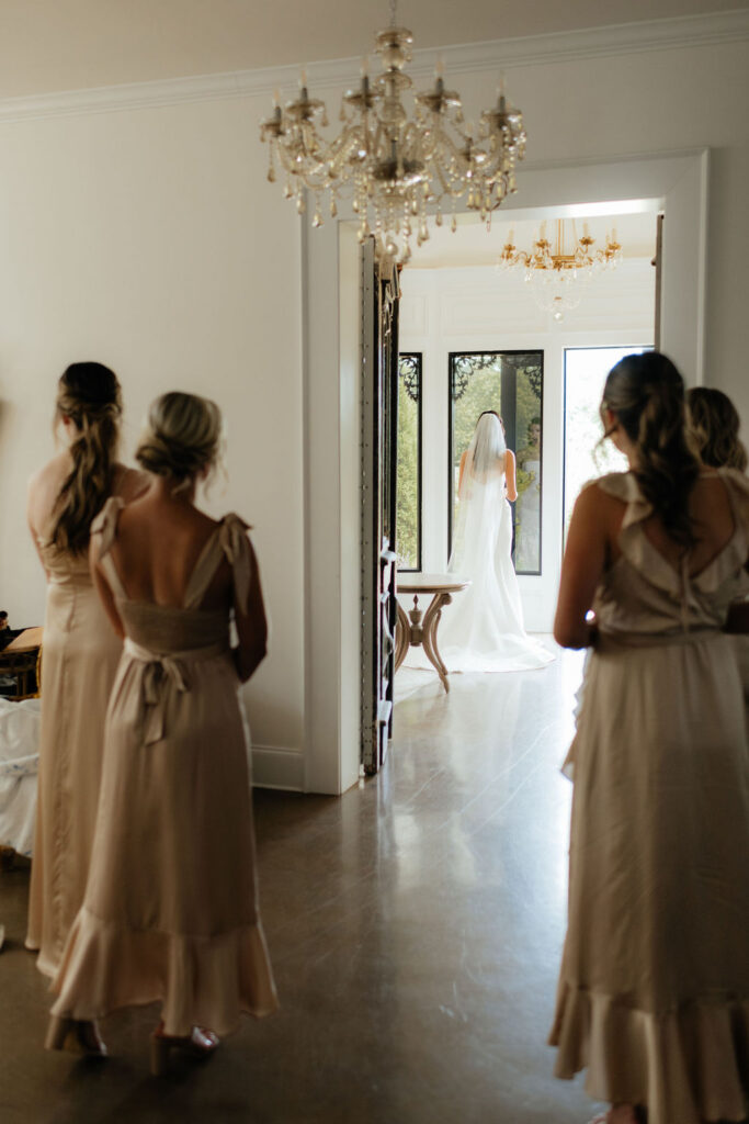 bridesmaids look on while a bride looks out the window of howe farms wedding venue in chattanooga tn