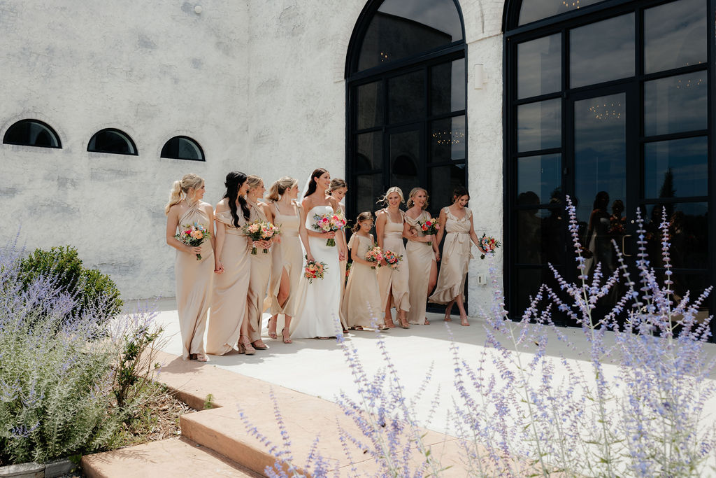 a bride and her bridal party walk along the exterior of how farms wedding venue in chattanooga tn