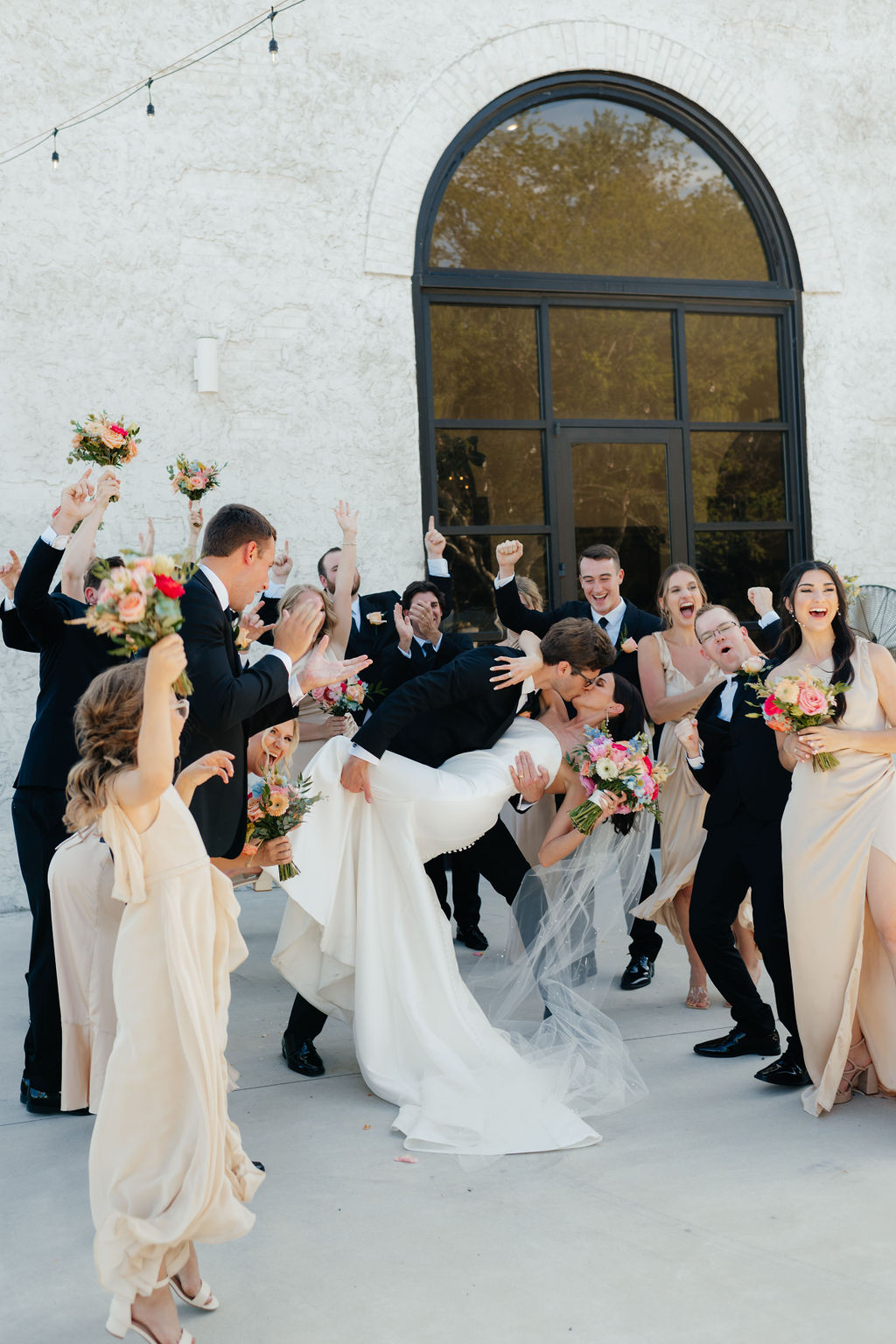 a wedding party cheers while the bride and groom kiss after their wedding ceremony at howe farms in chattanooga tn