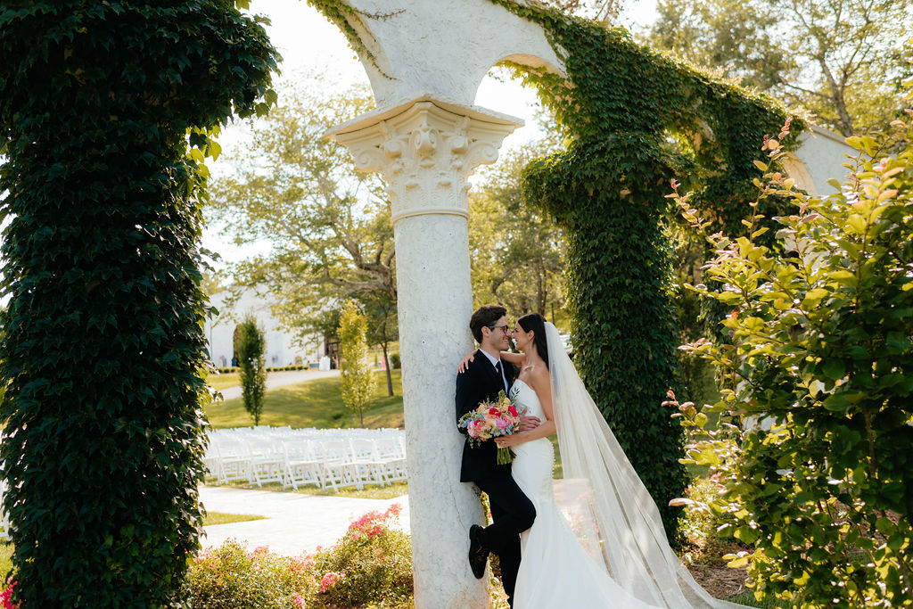 a bride and groom lean against ivy covered columns, their ceremony site at howe farms, their wedding venue in chattanooga tn