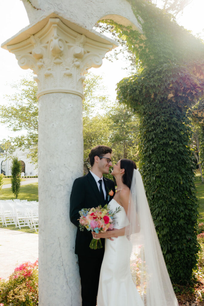 a bride and groom lean against ivy covered columns, their ceremony site at howe farms, their wedding venue in chattanooga tn