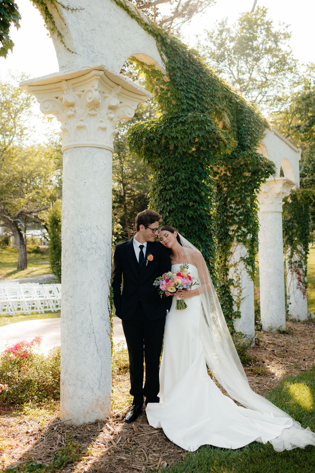 a bride and groom lean against ivy covered columns, their ceremony site at howe farms, their wedding venue in chattanooga tn