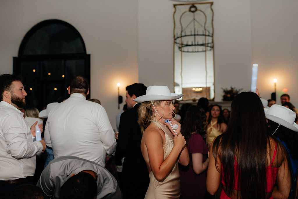 a bridesmaid dons a cowboy hat and dances during a wedding reception in chattanooga, tennessee at howe farms