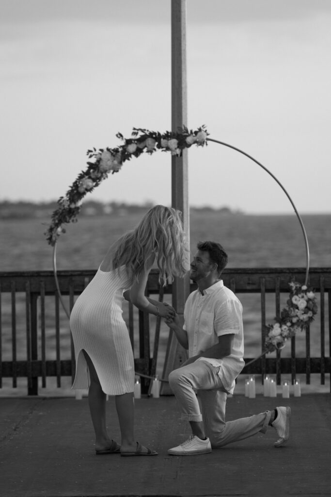 Man proposes on bended knee during a surprise proposal at Fairhope Municipal Pier, Alabama. Photos taken by Sarah Mismash Photography