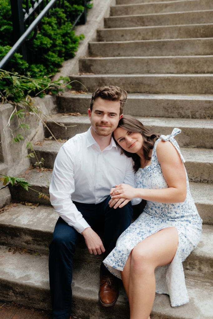 a couple sits together on the staircase from downtown huntsville to the big spring park and canal during their engagement photos with alabama wedding photographer Sarah Mismash