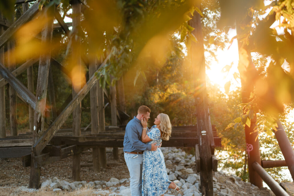 a couple laughs together at sunset during their engagement photos at the downtown Tuscaloosa riverwalk with alabama wedding photographer Sarah Mismash