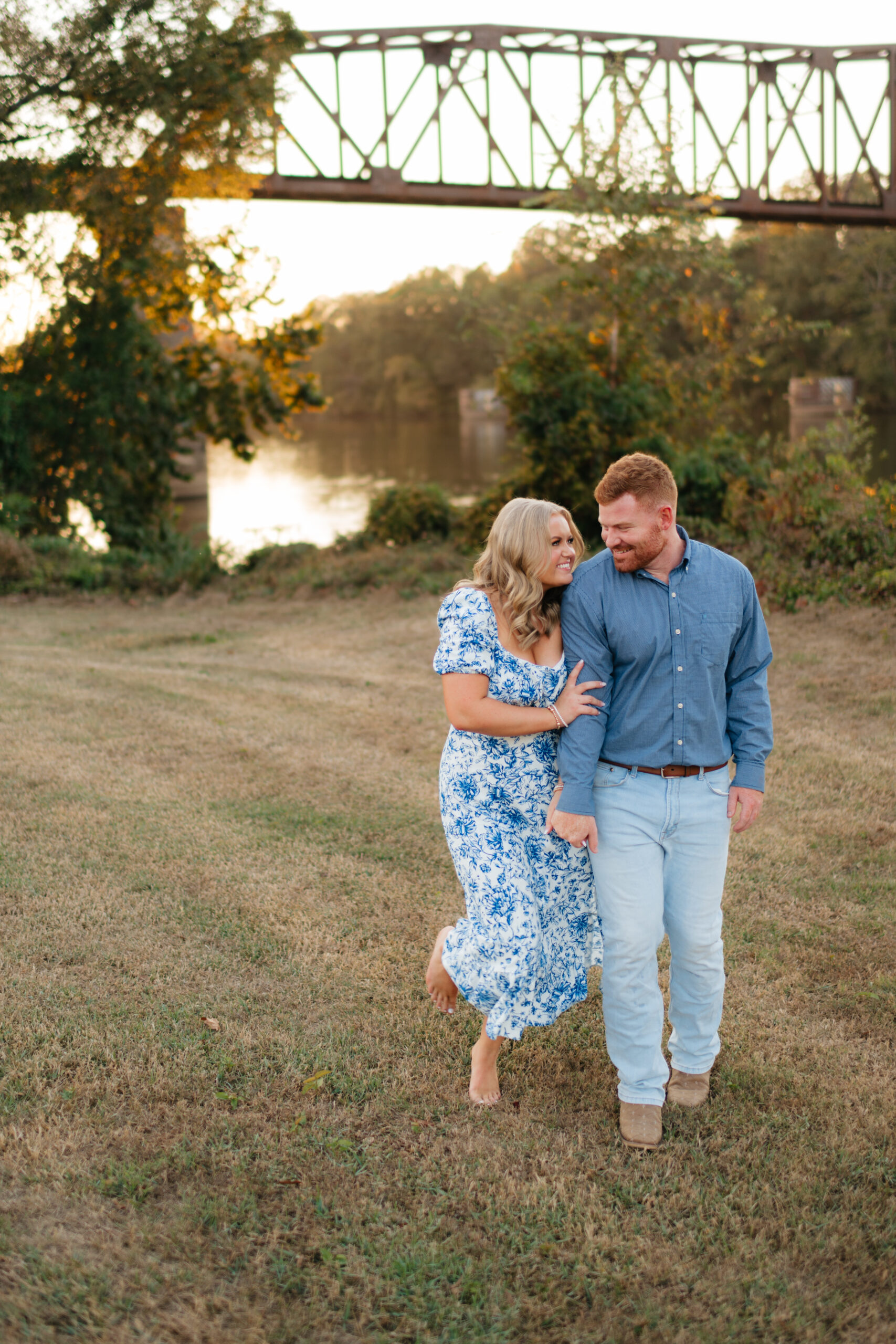 a couple walks along the downtown Tuscaloosa riverwalk during their engagement photos with alabama wedding photographer Sarah Mismash