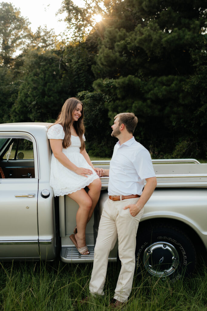 a couple sits in their pickup truck during their a couple sits in the grass during their summer field engagement photos in calera, alabama, photography by Birmingham alabama wedding photographer Sarah Mismash