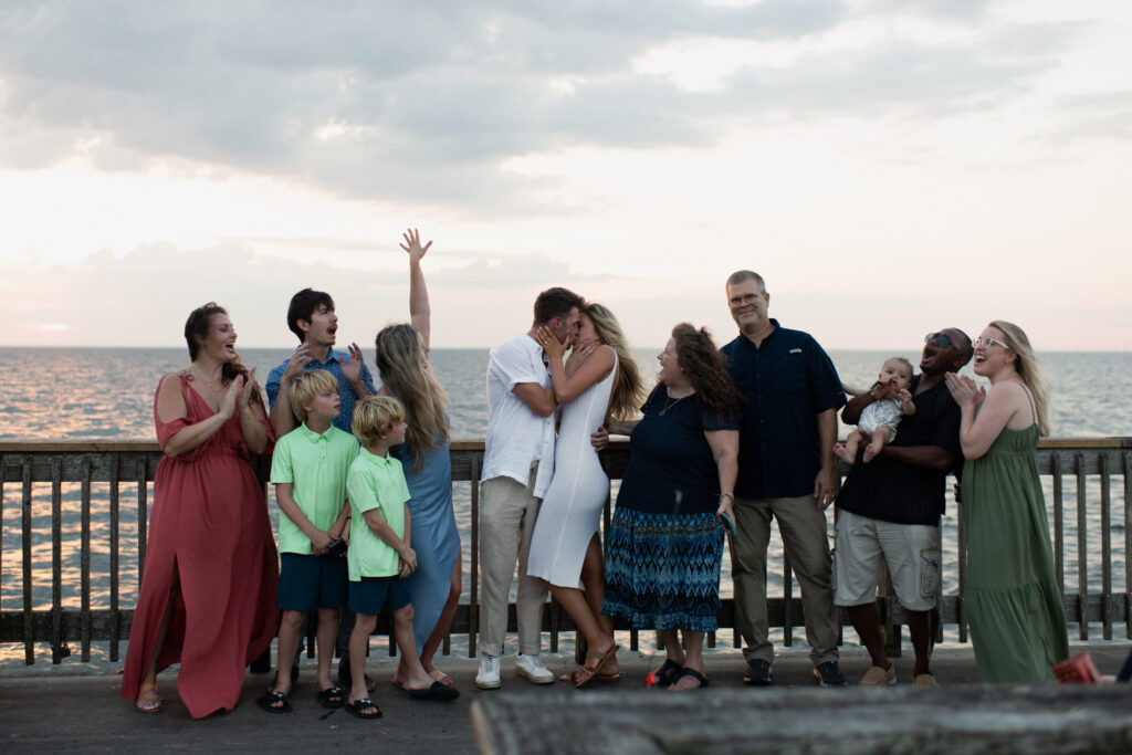 family members celebrate after a surprise proposal at Fairhope Municipal Pier, Alabama. Photos taken by Sarah Mismash Photography