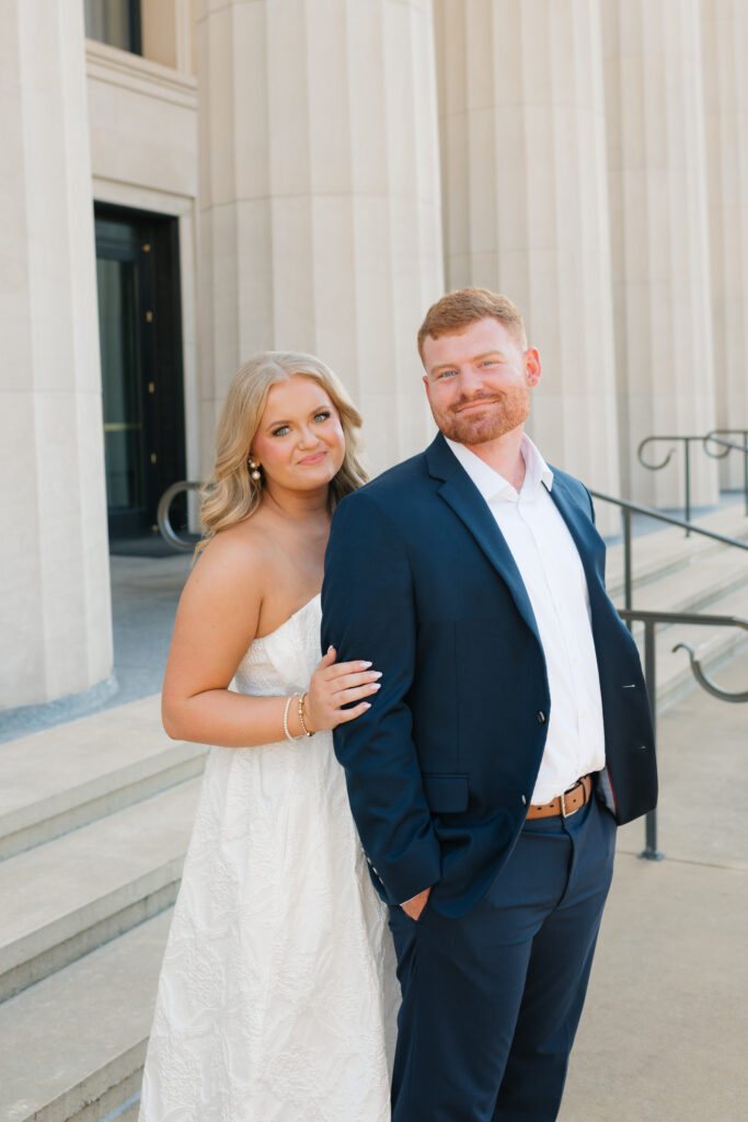 a couple smiles at alabama engagement photographer Sarah Mismash during their photos at the federal building in downtown tuscaloosa