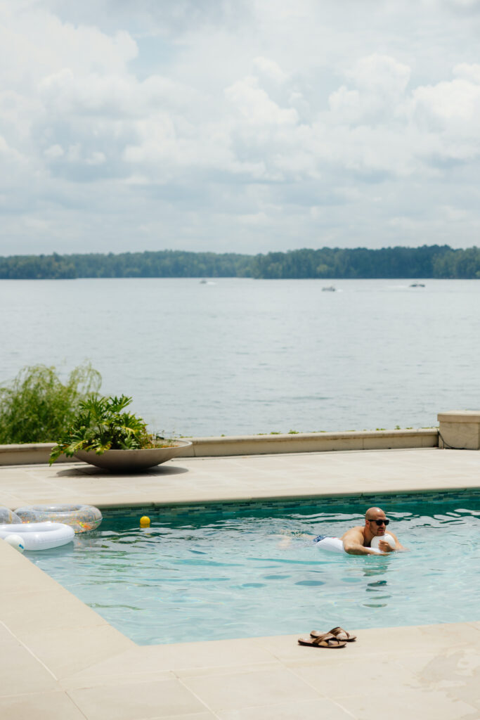 a groom swimming in the pool at his wedding venue on lake Martin on wedding morning while his fiance gets ready, photographed by alabama wedding photographer Sarah Mismash