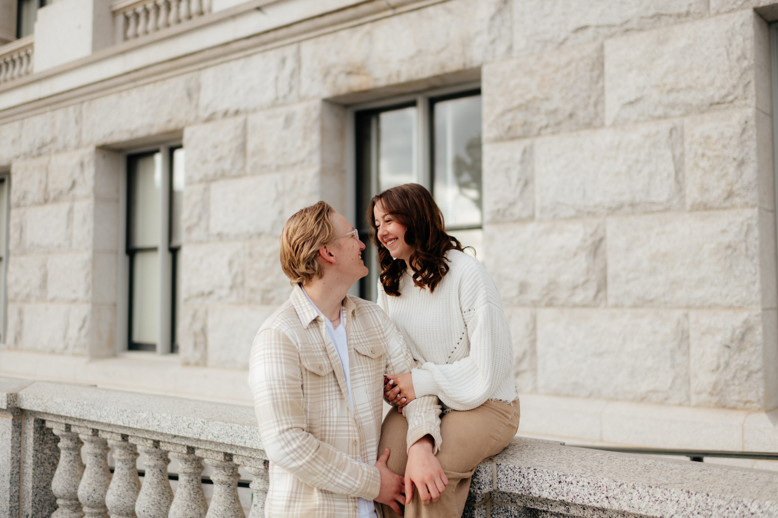a couple laughs together at the state capitol building during their engagement photos with olympia engagement photographer sarah mismash