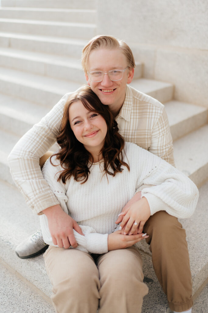 a couple sits together on the steps of the utah state capitol during their engagement photos with seattle washington engagement photographer sarah mismash