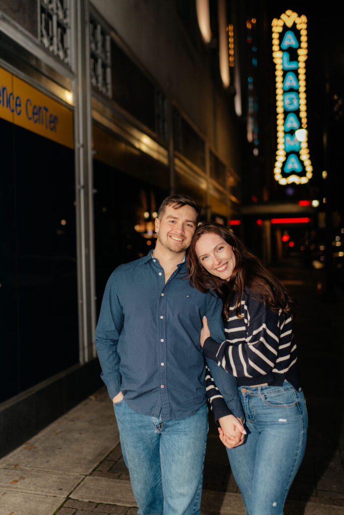 a couple holds hands near the alabama theater in downtown birmingham, AL during their urban winter engagement photos
