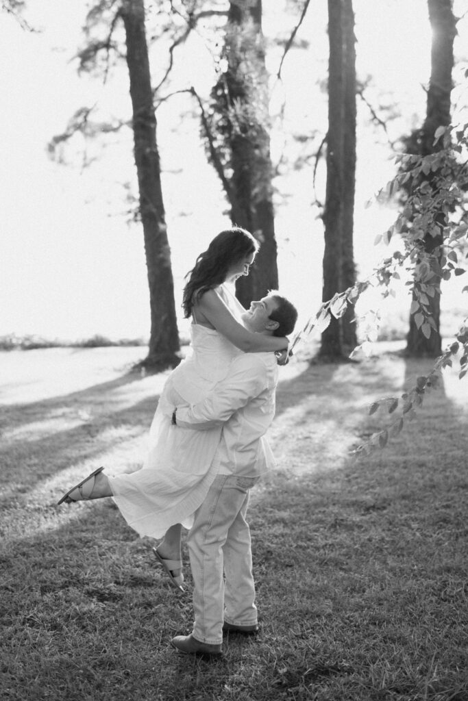 a man picks up his fiance and spins her around during their lakeside engagement photos in guntersville, alabama
