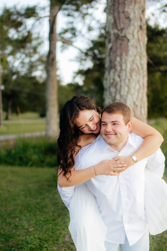 a man gives his fiance a piggy back ride during their engagement photos at Guntersville Lake with alabama wedding photographer Sarah Mismash