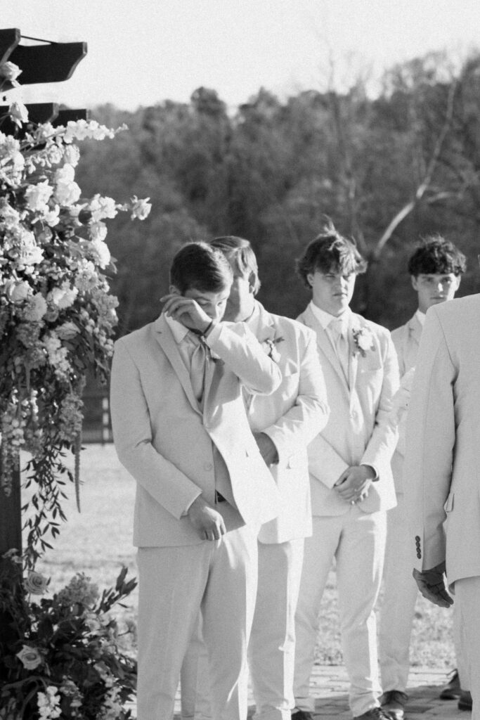 a groom wipes away a tear as his bride walks down the aisle to him during his wedding ceremony. photographed by seattle washington wedding photographer Sarah Mismash