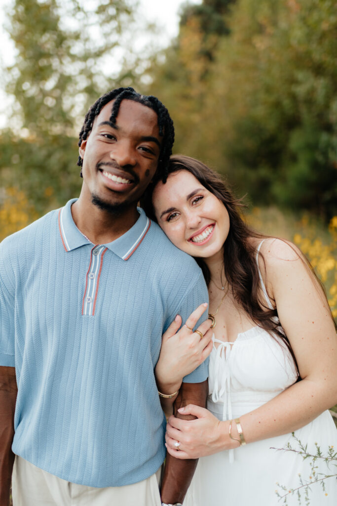 a couple snuggles in the wildflowers during their engagement photos with Olympia engagement photographer Sarah Mismash
