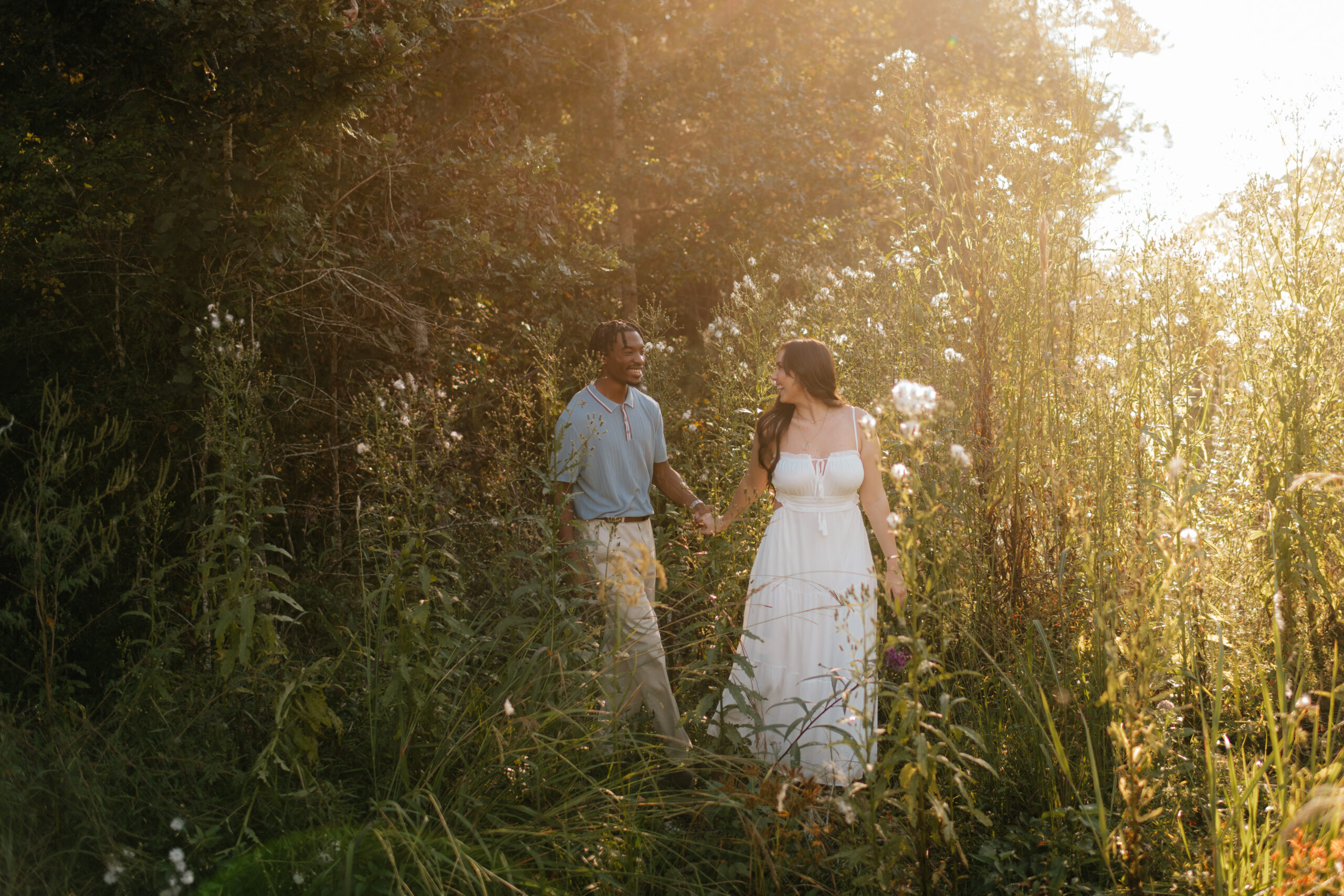 a couple walks through a wild field together during their engagement photos with washington wedding photographer Sarah Mismash