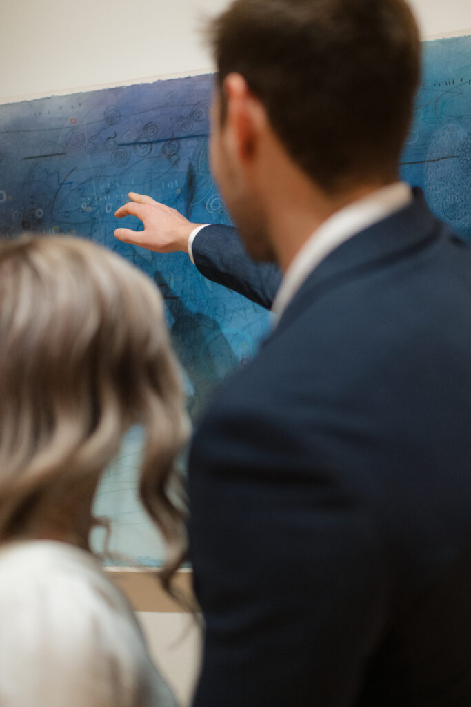 an engaged couple looks at paintings together during their engagement photos at the Seattle Art Museum with seattle engagement photographer Sarah Mismash