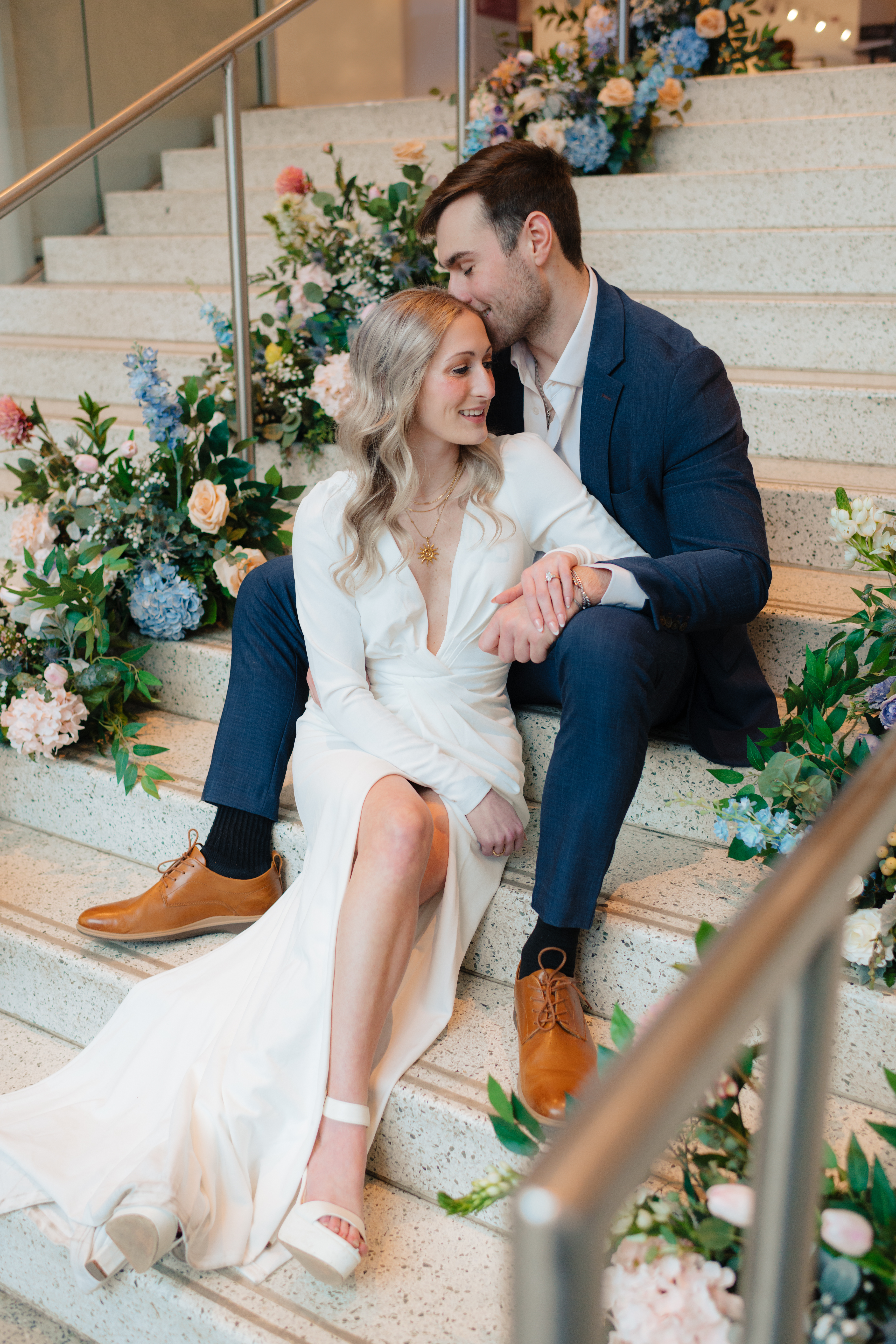 a couple sits on a staircase decorated for an exhibit opening during their engagement photos at the Seattle Art Museum with seattle engagement photographer Sarah Mismash