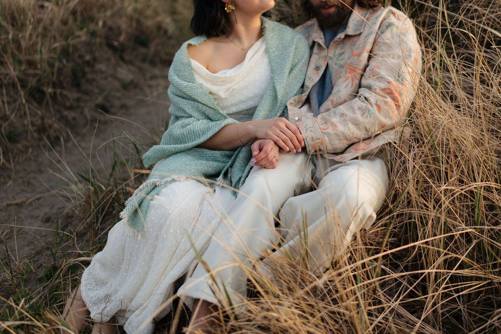 a couple watches the sunset from the dunes at twin harbors state park during their engagement photos on the washington coast with Westport washington engagement photographer Sarah Mismash
