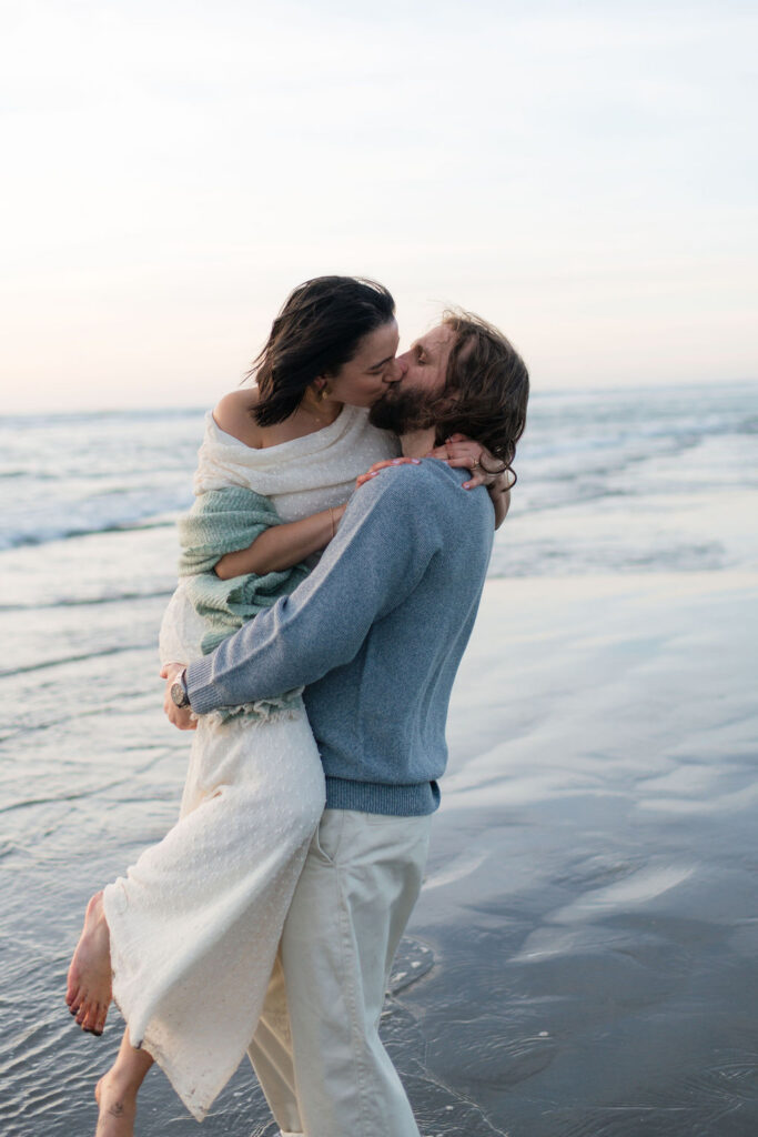 a couple kisses during sunset at twin harbors state park during their engagement photos on the washington coast with Westport washington engagement photographer Sarah Mismash