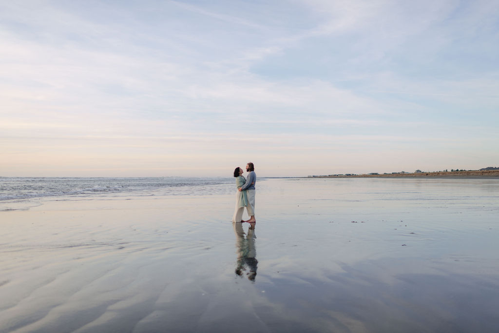 a couple holds each other during sunset and blue hour at twin harbors state park during their engagement photos on the washington coast with Westport washington engagement photographer Sarah Mismash