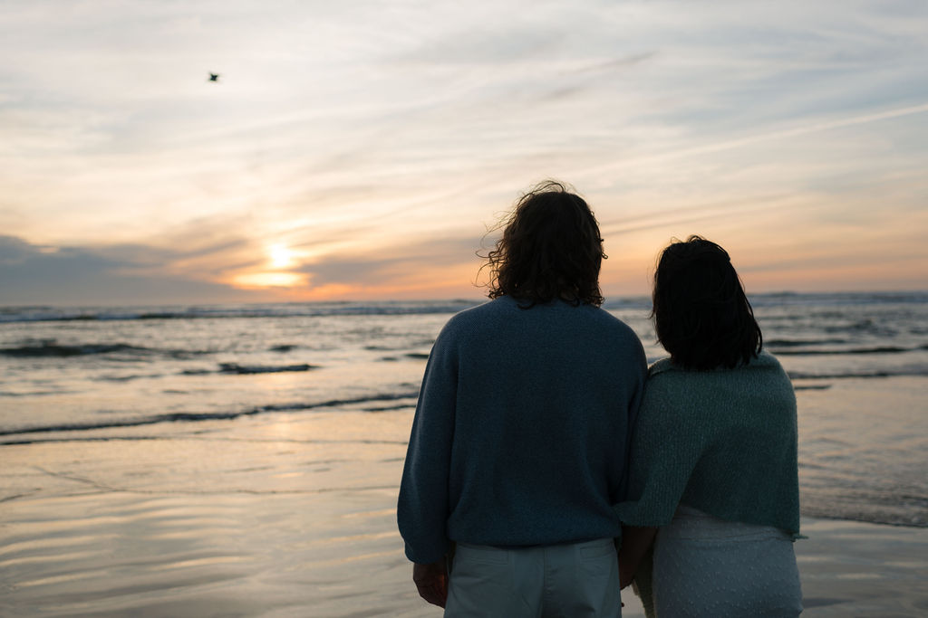 a couple watches the sunset at twin harbors state park during their engagement photos on the washington coast with Westport washington engagement photographer Sarah Mismash