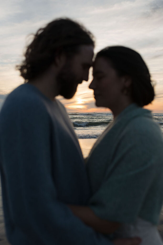 a couple touches foreheads during the sunset at twin harbors state park during their engagement photos on the washington coast with Westport washington engagement photographer Sarah Mismash