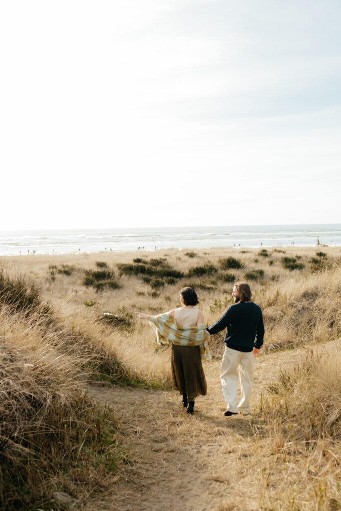 a couple looks out at the dune trail at twin harbor state park during their engagement photos with washington engagement photographer sarah mismash