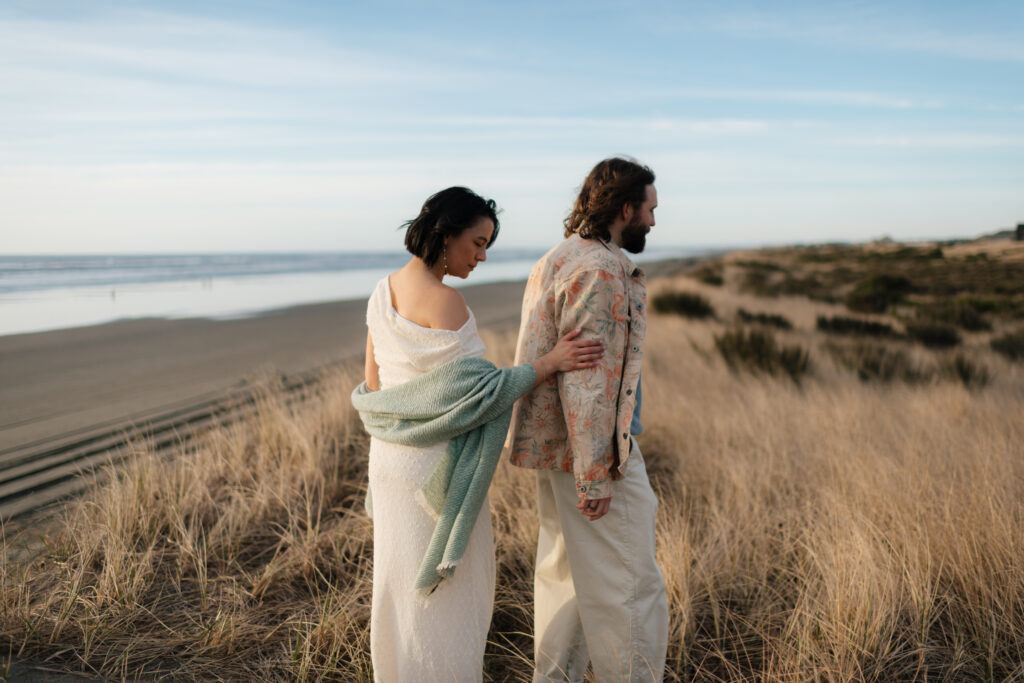 a couple walks through the dunes during their engagement photos with westport, washington engagement photographer sarah mismash