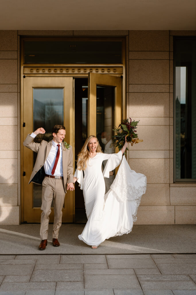 a couple cheers as they exit the oquirrh mountain utah temple after their sealing on wedding day