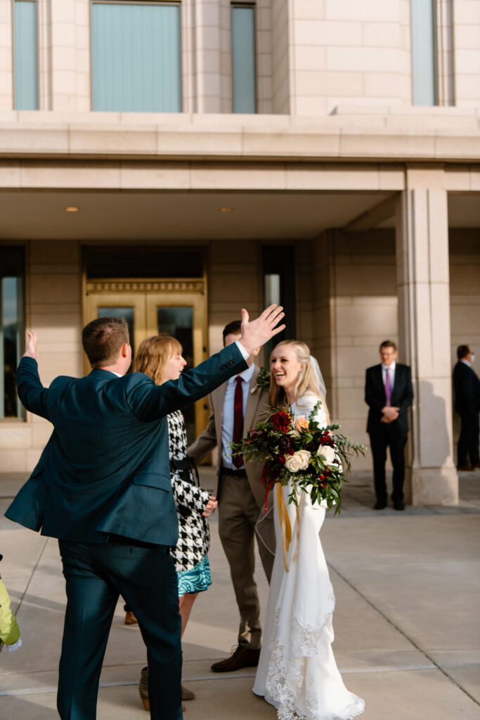 wedding guests greet and hug a couple after their temple sealing