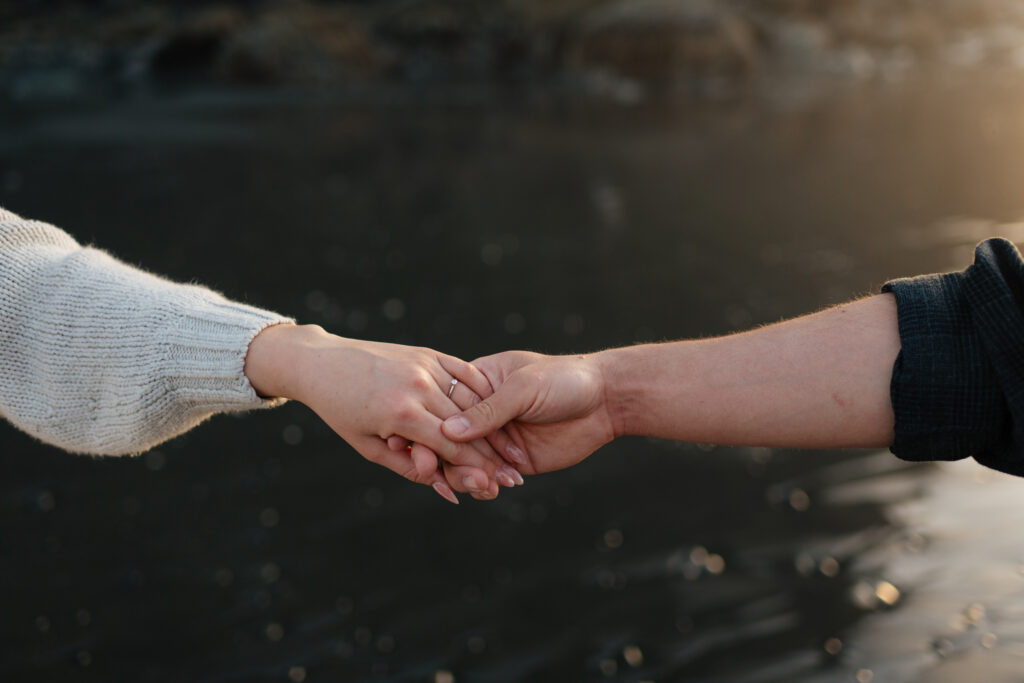 a couple holds hands during their ruby beach engagement photos in the pnw