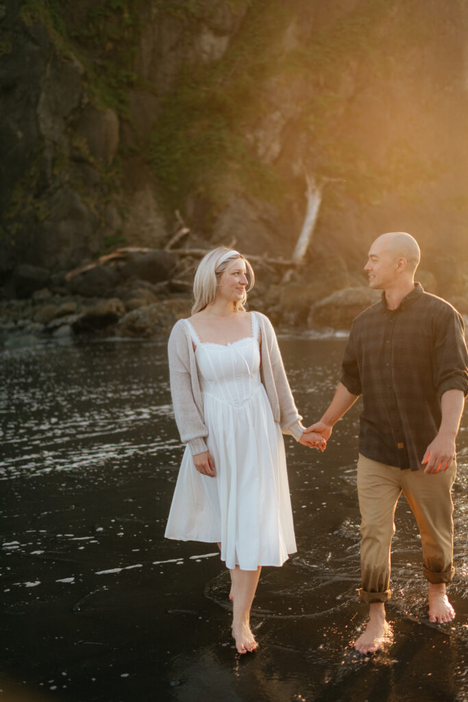 a couple runs across ruby beach during golden hour during their summer engagement photos on the washington coast
