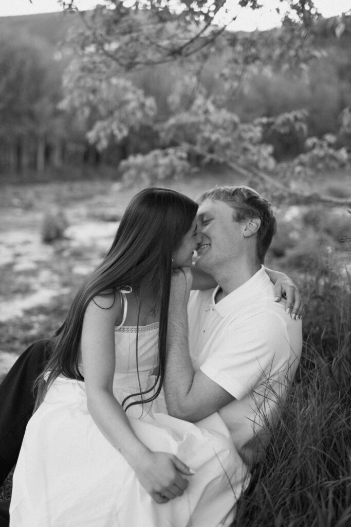 a couple kisses by the spring during their summer engagment photos in the alpine loop at american fork canyon and provo canyon, photographed by utah county engagement photographer sarah mismash