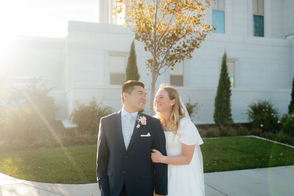 a couple smiles at sunset at the orem utah temple during their bridal portraits with orem wedding photographer sarah mismash