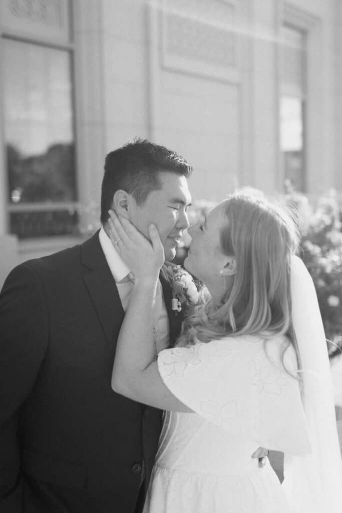 a couple goes in for a kiss during their september bridal portraits at the orem temple