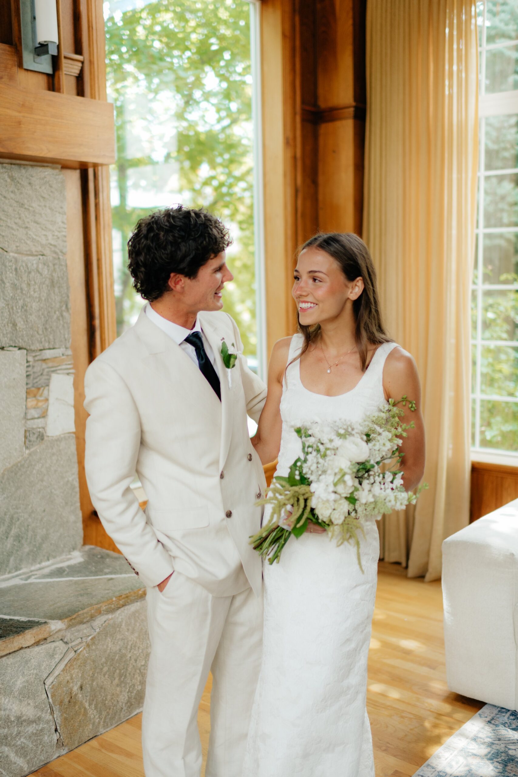 Bride and groom laughing together by a window during first look photographed by utah wedding photographer sarah mismash