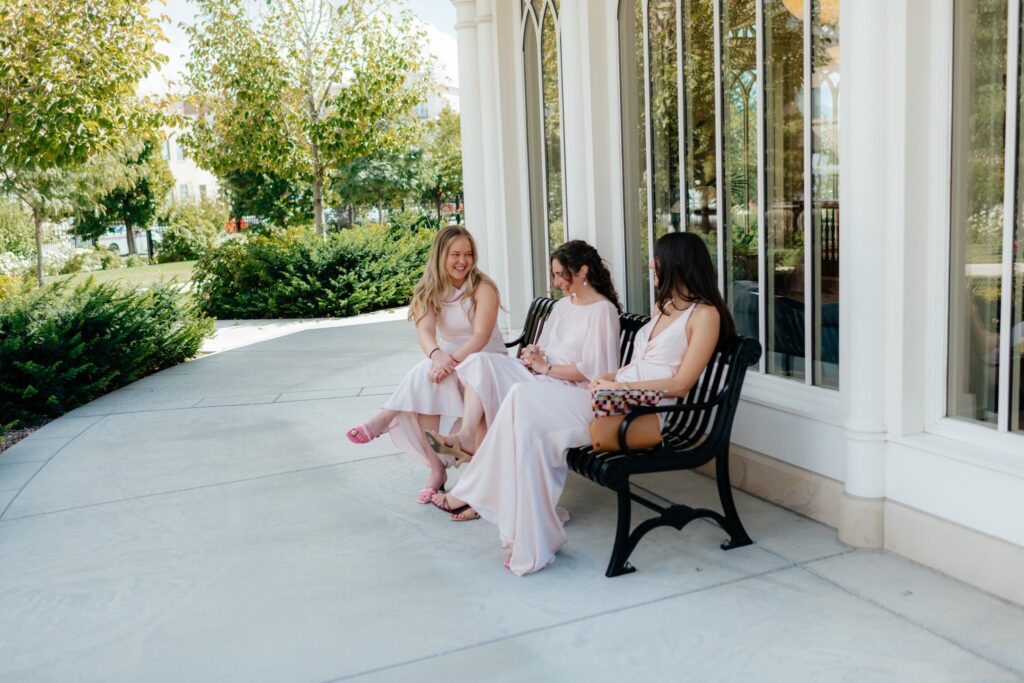 Bridesmaids sit together on a bench outside the Provo City Center Temple before the sealing begins.