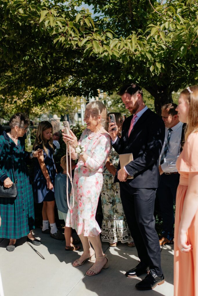 wedding guests take a video of the bride and groom during their temple exit at the provo city center temple