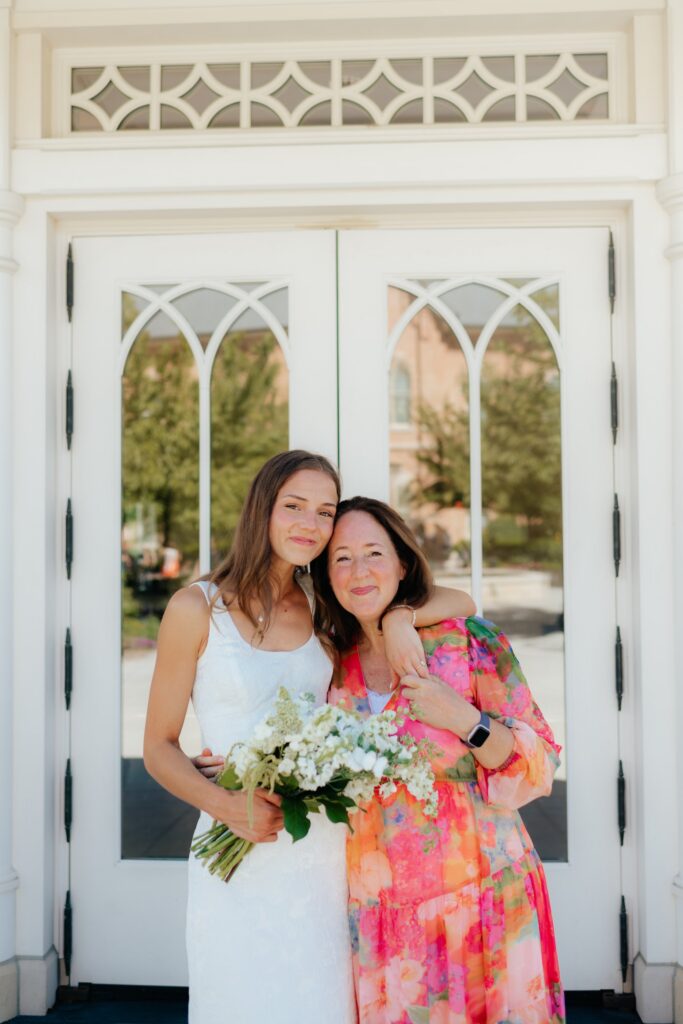 Bride and her mother posing in front of temple doors at the provo city center temple on a september afternoon