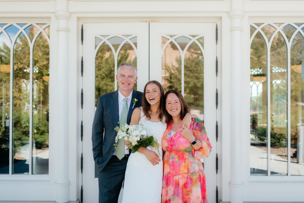 Bride and her parents laughing in front of the temple doors at the provo city center temple on a september afternoon
