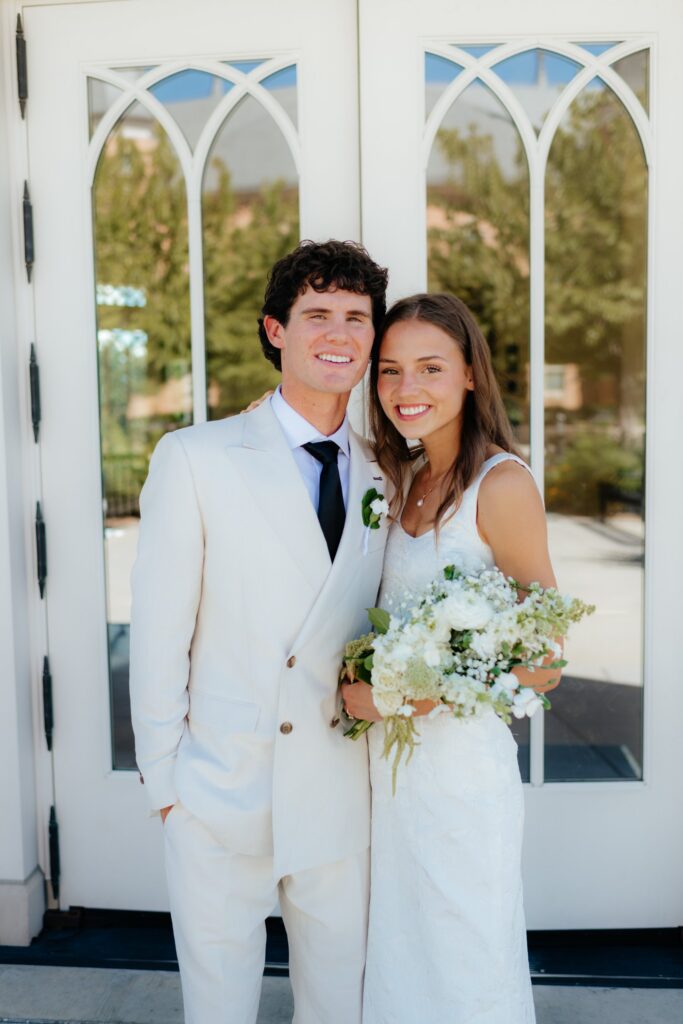 a couple laughs together outside the provo city center temple gazebo during their wedding portraits on the temple grounds