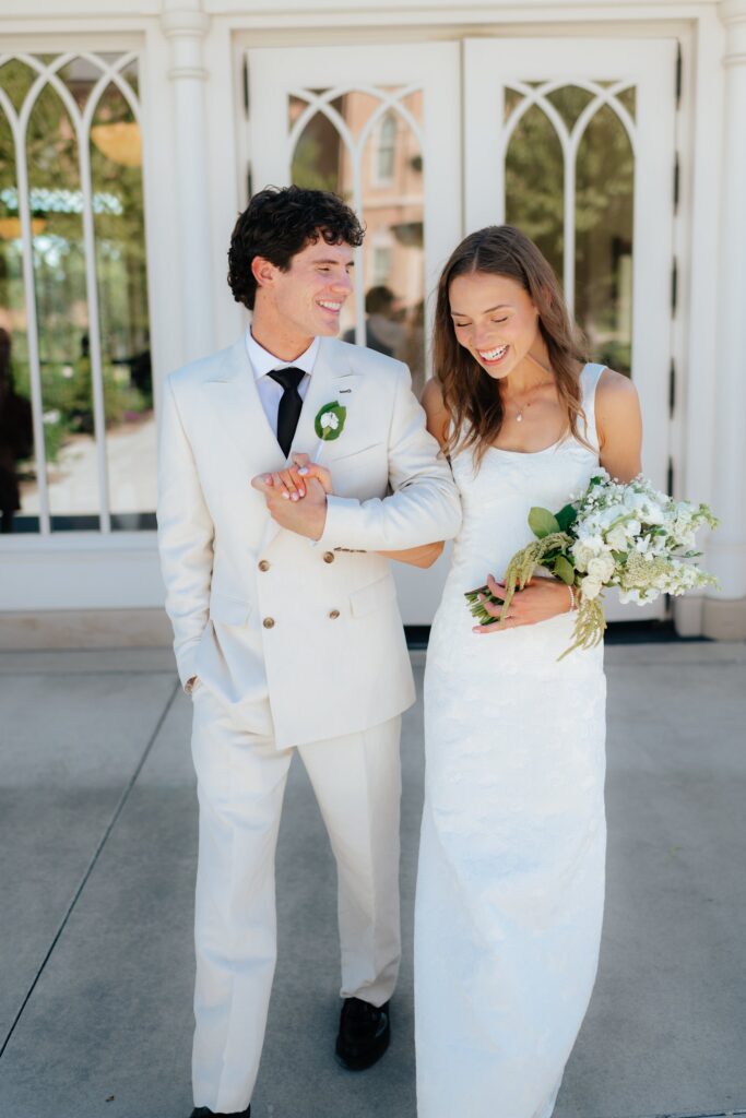 a couple laughs together outside the provo city center temple gazebo during their wedding portraits on the temple grounds