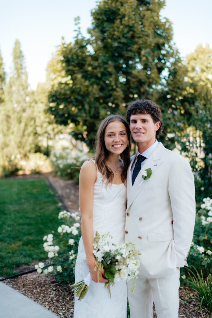 a couple smiles for utah temple wedding photographer sarah mismash during their wedding portraits at the provo city center temple grounds in september