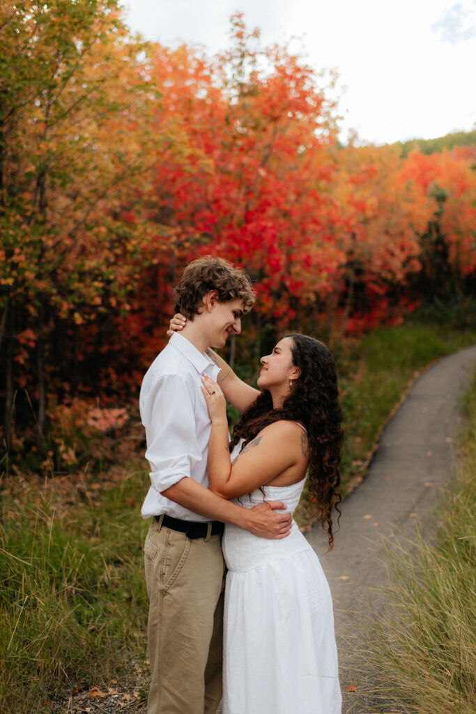 a couple smiles together during their fall engagement photos on the alpine loop in american fork canyon with utah engagement photographer sarah mismash